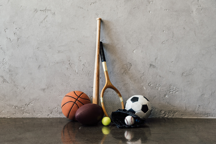 Close-up view of various balls and sports equipment near grey wall
